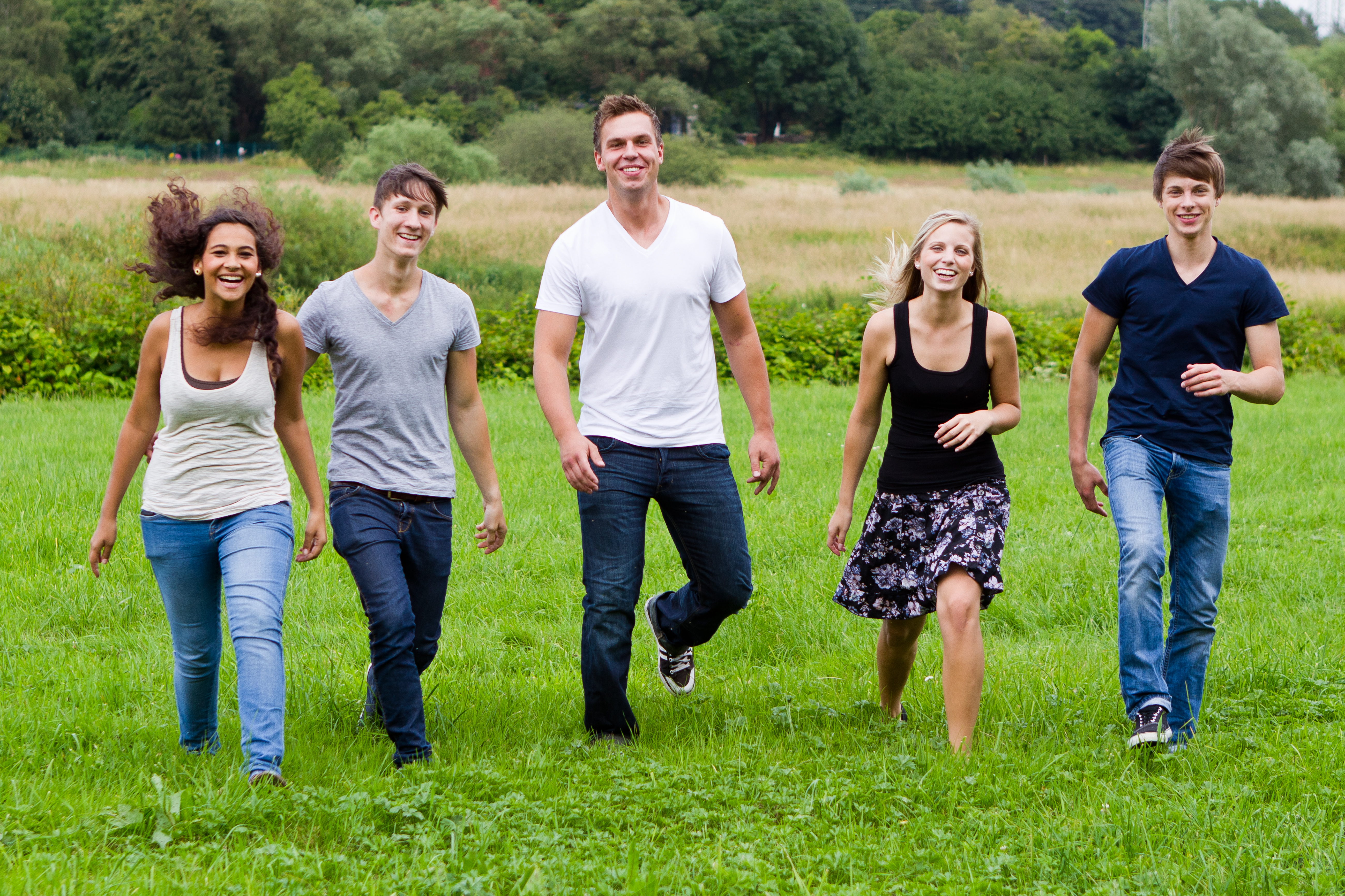 Fünf Jugendliche laufen auf einer Wiese.
