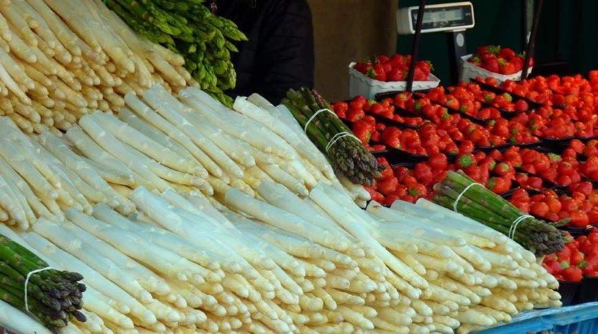 Spargel und Erdbeeren an einem Marktstand.