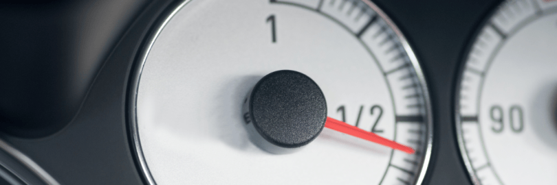 Die Tankanzeige eines Autos steht unter der Hälfte.