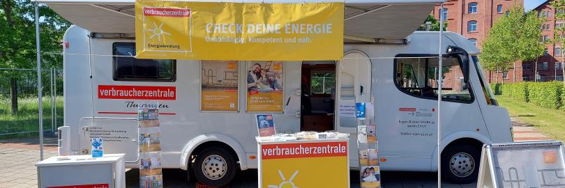 Zu sehen ist das Infomobil der Verbraucherzentrale Thüringen, ein weißes Wohnmobil mit Infotheke und Flyerständern.
