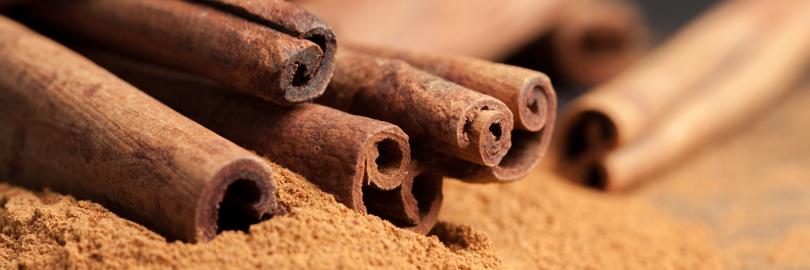 Cassia-Zimtrollen und gemahlener Zimt liegen auf einem Tisch.