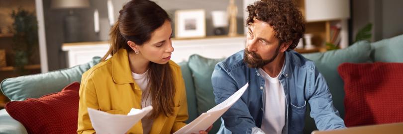 Ein Paar sitzt auf dem Sofa und prüft Vertragsunterlagen 