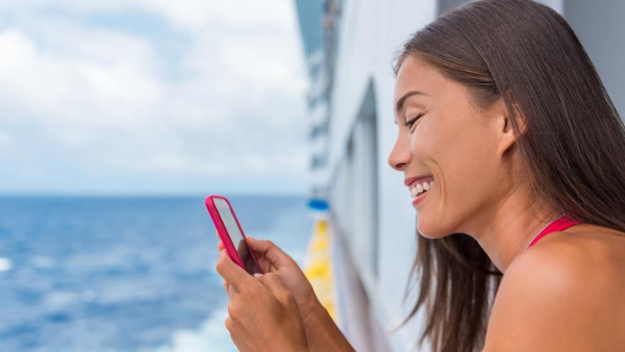 Eine Frau nutzt ihr Smartphone auf einem Kreuzfahrtschiff
