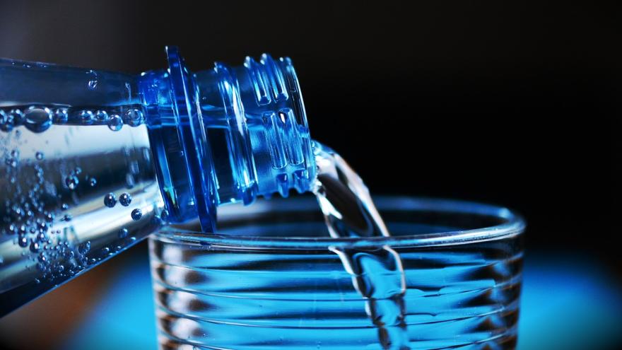 aus einer Flasche wird Wasser in ein Glas geschüttet