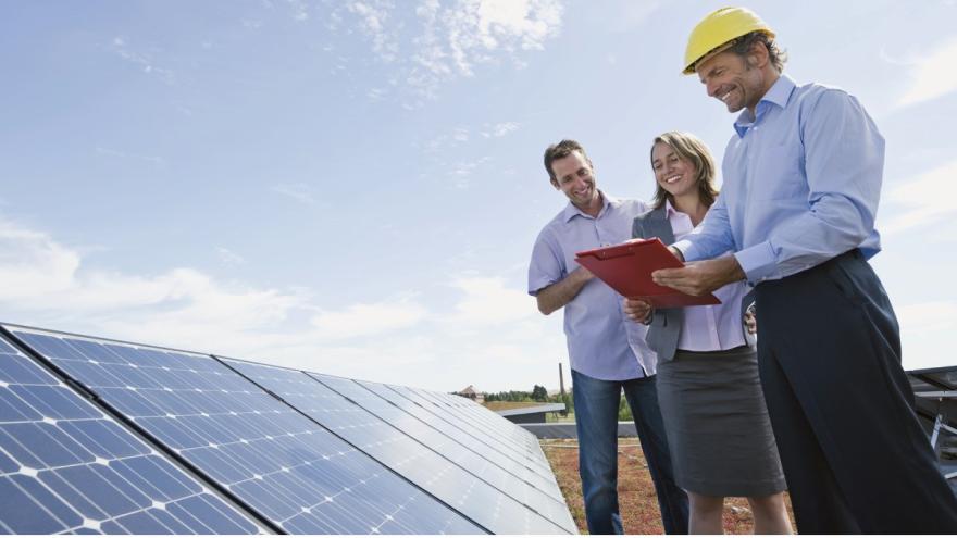 Ein Paar und ein Berater vor einer Solarstrom-Anlage