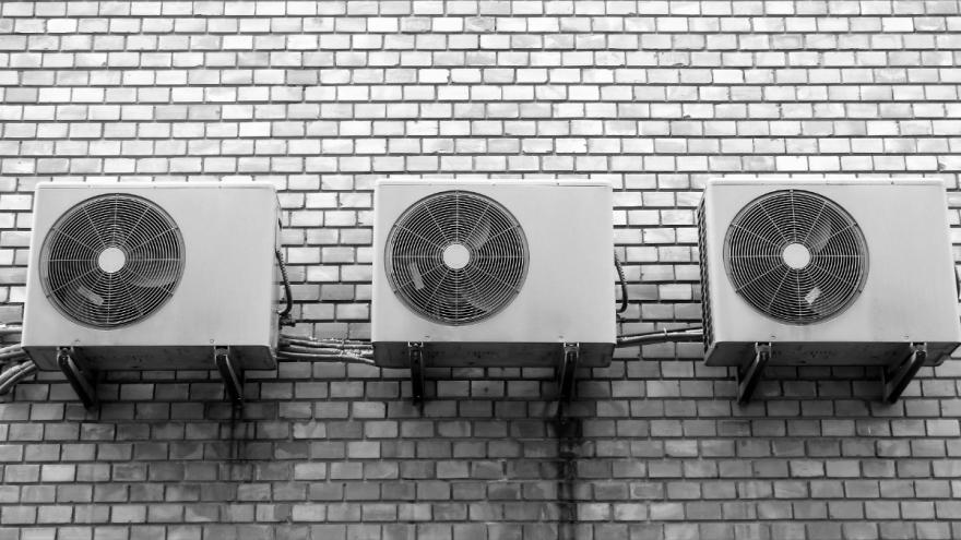 Drei Klimageräte hängen außen an einer Hauswand.