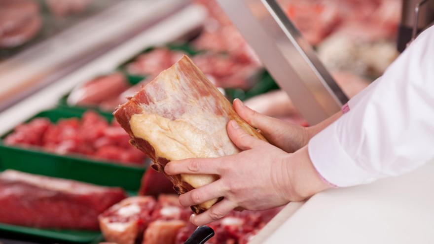Verkäufer nimmt ein Stück Fleisch aus Verkaufstheke