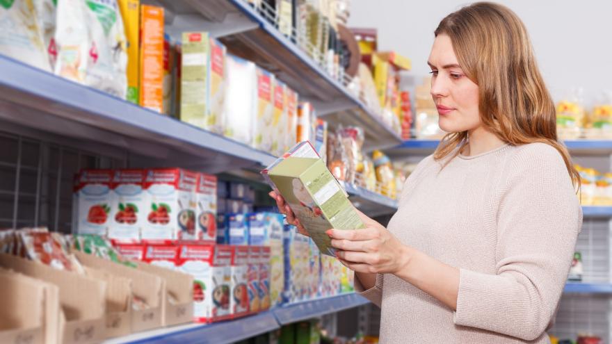 Eine Frau studiert Verpackungen beim Einkaufen in einem Supermarkt.