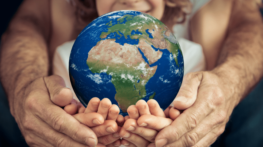 Drei Generationen Menschen halten gemeinsam einen Globus in den Händen.