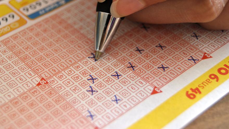Ein Verbraucher füllt mit einem Stift einen Lottoschein aus.