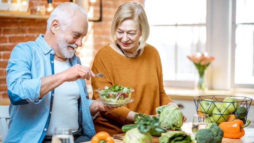 Ein Seniorenpaar bereitet gemeinsam Salat zu.