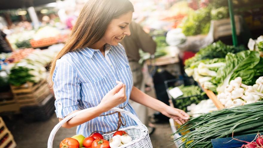 Eine Frau kauft auf einem Wochenmarkt in ihrer Region ein.