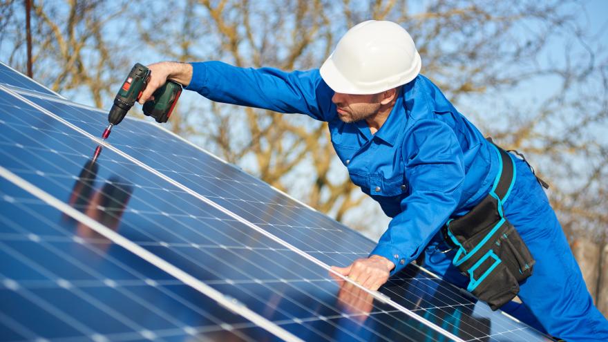 Techniker auf einem Dach installiert eine Photovoltaik-Anlage