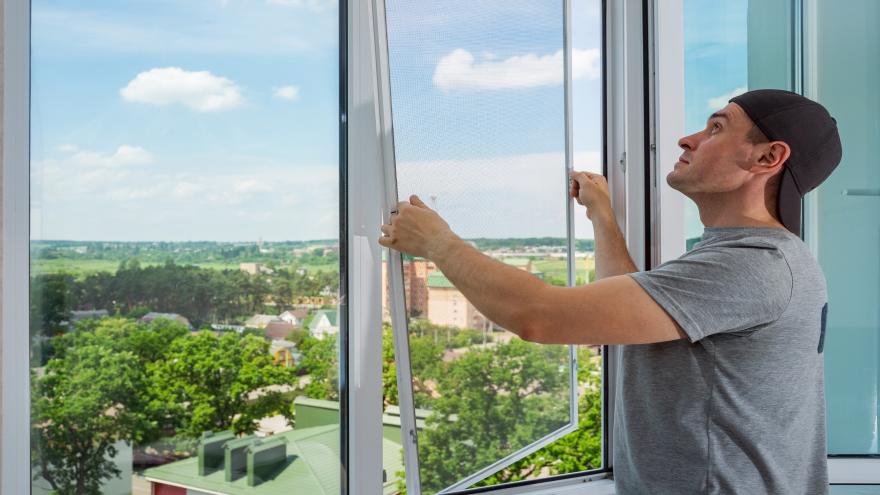 Ein Mann installiert ein Fliegenfenster