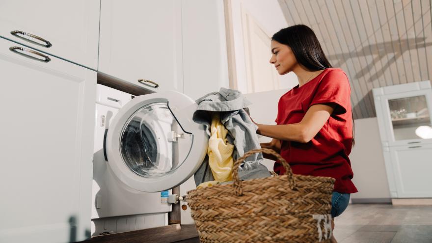 Eine Frau belädt eine Waschmaschine.