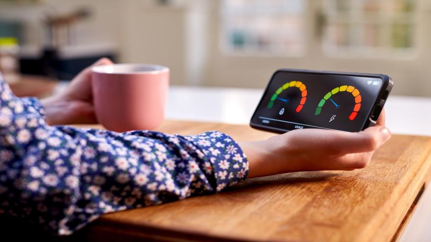 Eine Hand hält ein Smartphone mit der Anzeige des Strom- und Gasverbrauchs.
