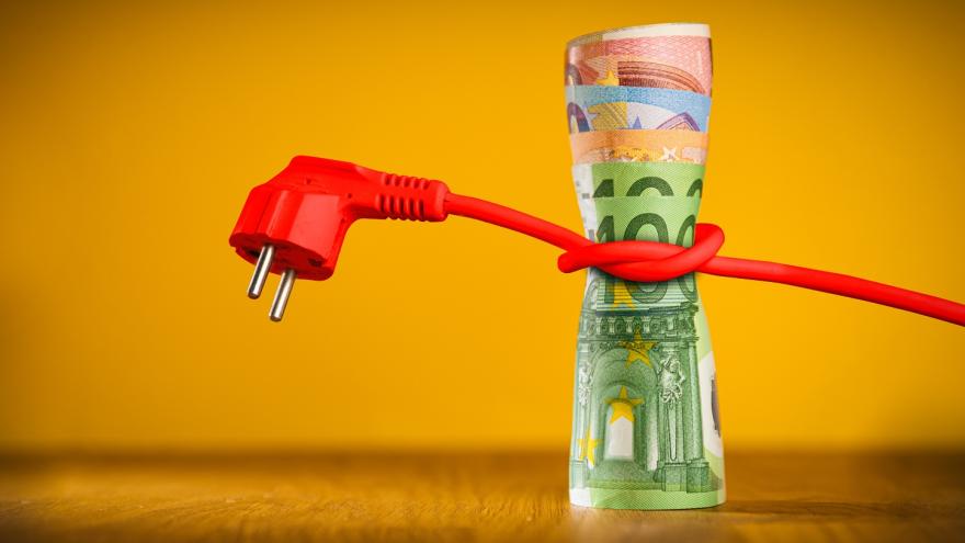 Ein rotes Stromkabel ist um ein Bündel Euro-Geldscheine gewickelt.