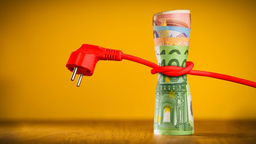 Ein rotes Stromkabel ist um ein Bündel Euro-Geldscheine gewickelt.