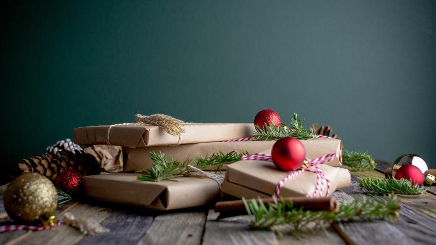 Weihnachtsgeschenke, die in Packpapier verpackt sind sowie Weihnachtskugeln und Tannen