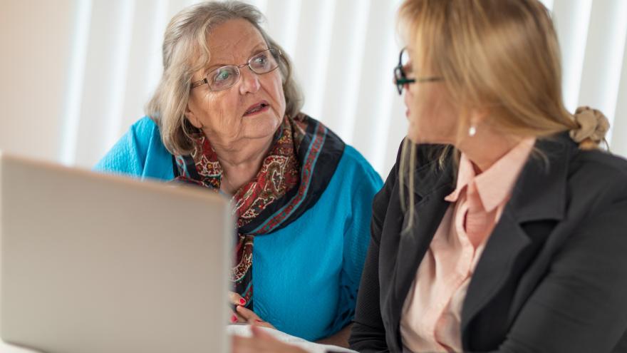 Zwei Frauen sprechen miteinander vor einem Laptop.