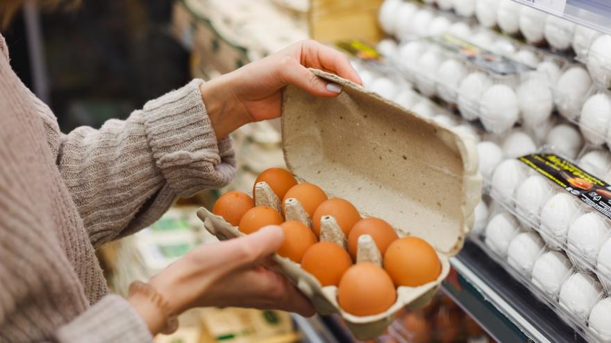Eine Frau öffnet einen Karton mit braunen Eiern in einem Supermarkt.