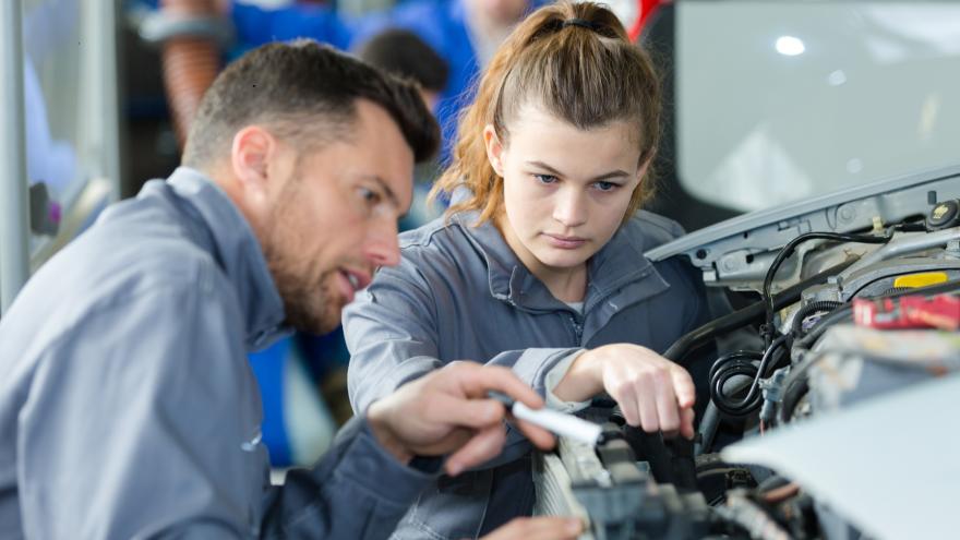 Eine junge Frau als Auszubildende in einer Autowerkstatt.