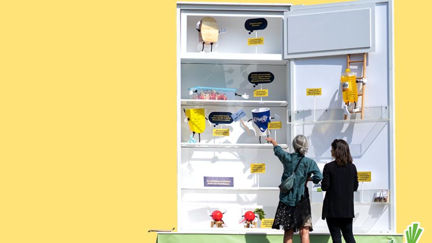 Zwei Frauen stehen vor einem überdimensionalen Kühlschrank.