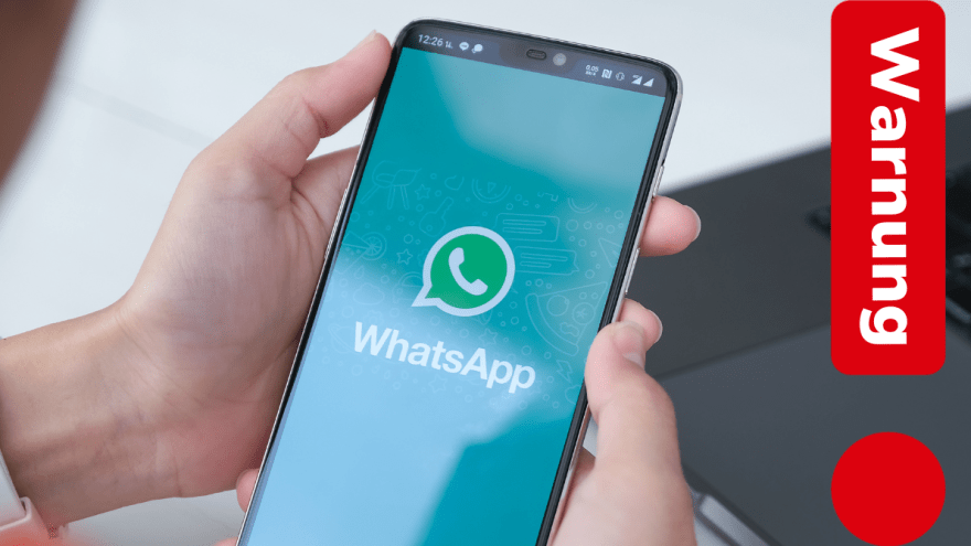 Jemand hält ein Smartphone, auf dem Display ist das WhatsApp-Logo zu sehen. Auf einem roten Ausrufezeichen steht "Warnung".