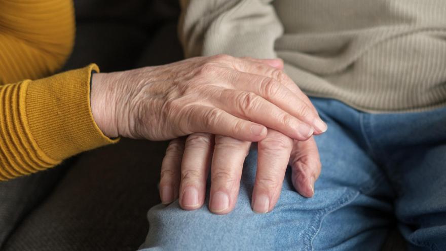 Die Hand einer Person auf der Hand einer anderen Person auf einem Oberschenkel.