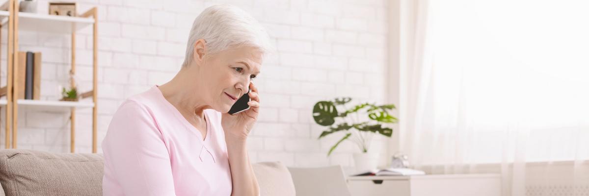 Eine Frau sitzt auf einem Sofa und telefoniert.