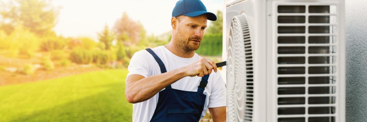 Ein Techniker arbeitet an der Außeneinheit einer Klimaanlage oder Wärmepumpe.