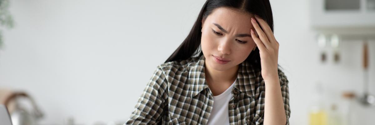 Eine Frau sitzt am Küchentisch mit einem Brief. Ihr Blick ist zweifelnd. 