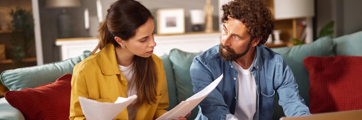 Ein Paar sitzt auf dem Sofa und prüft Vertragsunterlagen 