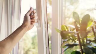 Eine Hand öffnet ein Fenster. 