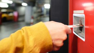 Ein Fahrgast zieht ein Ticket über einen Fahrkartenautomaten.