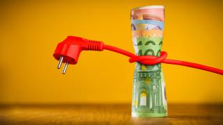 Ein rotes Stromkabel ist um ein Bündel Euro-Geldscheine gewickelt.