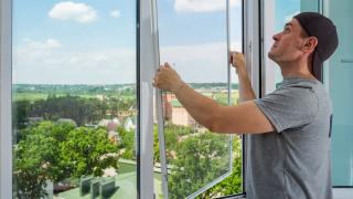 Ein Mann setzt ein Fliegengitter ein.