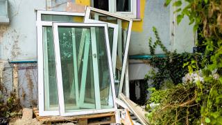 Neue Fenster lehnen an einer Hauswand.