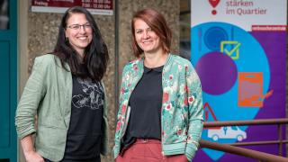 Zwei Mitarbeiterinnen der Verbraucherzentrale Thüringen stehen vor einem Rollup.