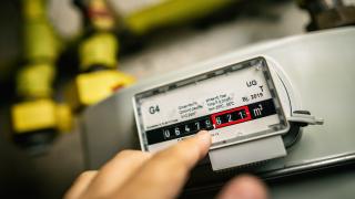 Finger zeigt auf Gaszähler mit Zählerstand im Keller.