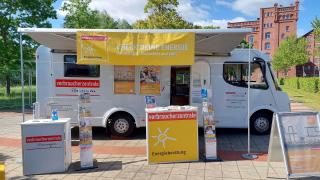 Zu sehen ist das Infomobil der Verbraucherzentrale Thüringen, ein weißes Wohnmobil mit Infotheke und Flyerständern.
