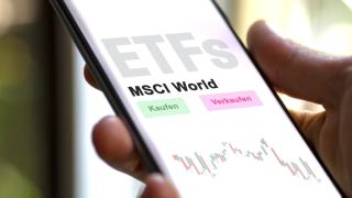 Eine Hand, die ein Smartphone hält, auf dem "ETFs, MSCI World" und "Kaufen" und "Verkaufen" zu lesen ist