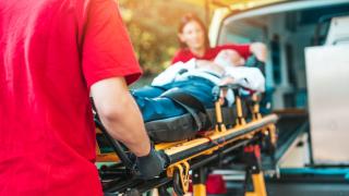 Zwei Sanitäter schieben eine Bare mit einem Patienten in einen Krankenwagen