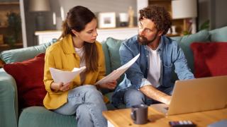 Ein Paar sitzt auf dem Sofa und prüft Vertragsunterlagen 