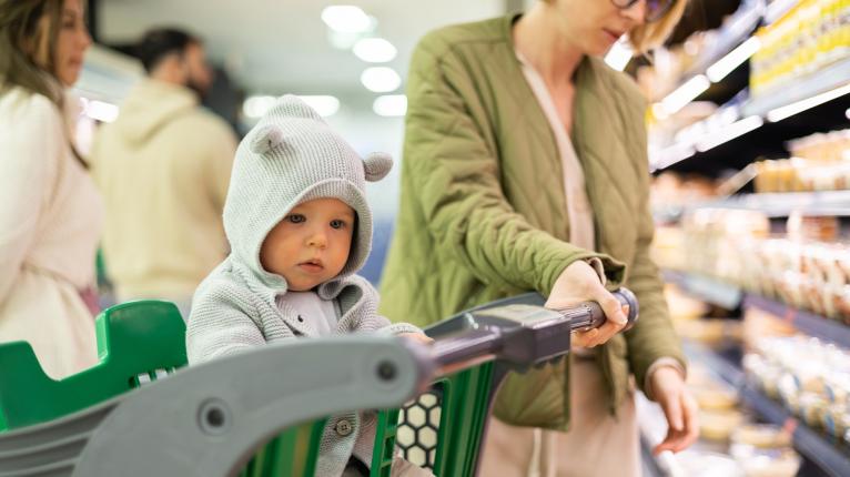 Ein Baby sitzt in einem Einkaufswagen im Supermarkt.
